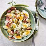 Op tafel staat een diep bord met hierin al een klaargemaakte aardappelsalade. Wij combineren hem met een gekookt eitje, spek, augurkjes en een dressing op basis van yoghurt en pittige mosterd.