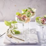 Drie garnalencocktails staan geserveerd op een marmer aanrecht, in mooie wijnglazen met een brede opening bovenaan. Er liggen gouden vorkjes naast om het feestgehalte een extra boost te geven. 