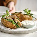 Twee gepofte aardappelen liggen op een plateautje, ze zijn gevuld met 