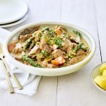 Deze fricassee straalt een en al lente uit! Hij is klaargemaakt met jonge worteltjes, erwtjes en aspergepunten. Er ligt gouden bestek langs en een portie gekookte aardappelen.
