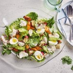 Een goed gevulde schaal met een groene salade, enkele oranje wortels en gekookte eitjes. Stukjes rode poon werden toegevoegd voor extra smaak, natuurlijk.