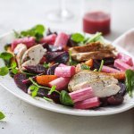 Een rijkgevuld salade die gezond is en mooi van kleur, daar word je instant vrolijk van. De salade bestaat uit frisgroene spinazie, warmoranje wortel, bloedrode bietjes, zoetroze rabarbar en goudgegrilde kip. De frambozendressing werd erbij geserveerd in een glazen kannetje. 