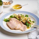 Er staat een bordje op tafel, gevuld met de kleurrijke én rijke salade. Er liggen ook enkele sneetjes varkensgebraad bij. Je kan extra salade scheppen en vinaigrette.
