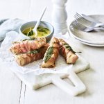 Op een snijplankje ligt de klaargemaakt saltimbocca. Hij is mooi gegrild vanop de bbq te grillen. We serveren hem met het sausje op basis van boter, salie en witte wijn.