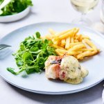 Een licht blauw bord staat op tafel, gevuld met frietjes, veldsla-slaatje en een saltimbocca van vis. Wij serveren hem met huisgemaakte bearnaisesaus. Een feestgerechtje dus. 