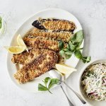 Vegetarische schnitzels gemaakt van aubergine. Ze liggen op een groot wit ovaal bord, waar je er eentje van kan afnemen. Wij serveren hem met een koolslaatje.