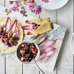 Taco’s met kip, roodlof en een salsa van braambessen en aardbei ligt klaar om op te eten. Er ligt al een tweede taco in de maak, op een marmere snijplank. De kleuren van roos tot donker rood van het fruit en loof geven een mooi contrast in de foto.