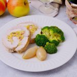 De varkensrollade ligt aangesneden op een bord. Twee ronde schijfjes met in het midden de vulling van appel en spek. We serveren deze varkensrollade met broccoli en de sjalotjes. 