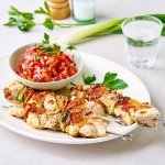 Enkele gegrilde brochettes liggen op een serveerschaal samen met een potje tomatensalsa. De salsa zorgt voor een mooie rode kleur bij de zeeduivelspiesjes.