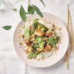 Een portie food is uitgeschept in een licht roze bord. Het is een portie rijst met daar bovenop de wok van konijn met paksoi en peultjes. Om af te werken zijn er wat pindanootjes toegevoegd en koriander.