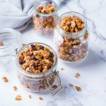 Homemade granola in 2 bokalen op het marmere aanrecht. 