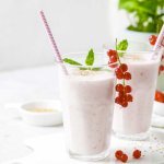 Een heerlijke lichtroze smoothie staat op tafel. Netjes naast de andere met een bosje verse munt erbij en nog enkele aardbeien. 