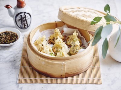 Dumplings met kip Er staat een stoommandje op het marmere aanrecht waarin verschillende dumplings liggen. Er staat bovenaan een dipsausje op basis van sojasaus en een chinees kannetje.