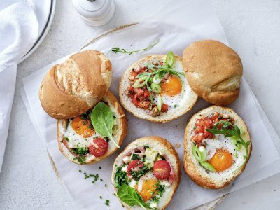 Eieren uit de oven met ham of tomatensalsa Gevulde broodjes met een eitje erin, staan op tafel te blinken! We maakte een versie met gekookte ham, courgette en tomaatjes. En onze tweede is er eentje met pittige tomatensalsa en rucola, heerlijk!