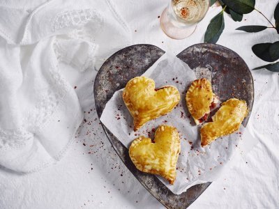 Empanadas gemaakt in hartjesvorm liggen op een bordje te schitteren. Met dit hapje scoor je sowieso bij je geliefde. 