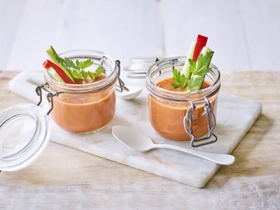 Twee bokaaltjes met gazpacho staan op een marmer plankje, een ideaal alternatief voor te weinig glazen. We gaven de gazpacho een feestlook met staafjes komkommer en paparika in het bokaaltje te laten op springen.  