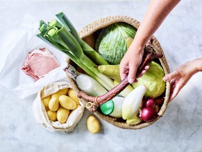Mand gevuld met producten recht van bij de boer Mand staat op het aanrecht en is gevuld met heerlijke producten van eigen bodem. Denk maar aan prei, witte kool, witloof, yoghurt, uien, krieltjes, varkensvlees... Klaar om meteen aan de slag te gaan.