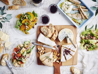 Originele kaasschotel met warm geitenkaasje en partjes peer De tafel staat klaar om aan te vallen. Er staat een kaasplank op met Belgische kazen en verschillende bijgerechten met fruit en groenten. Wijn en brood mogen natuurlijk niet ontbreken bij deze pittige kazen.