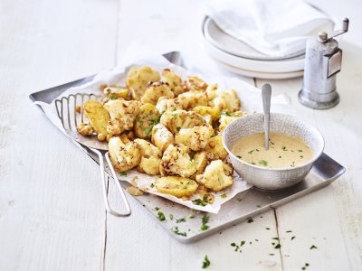 Ovenschotel met kikkererwten, bloemkool en krieltjes Een ovenschotel gevul de goud! Zo ziet hij er eigenlijk een beetje uit. De ovenschotel is bestaat nl uit kleine aardappelen, kikkererwten en bloemkoolroosjes. We dienen hem op met een heerlijk sausje op basis van tahini. Alles afgewerkt met groene snippers van de peterselie.