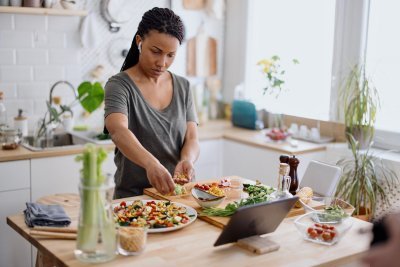 Vrouw maakt een salade van verschillende groenten in haar keuken