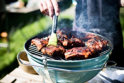 Ribbetjes op de bbq Ribbetjes op een barbecue in de tuin. De kok borstel nog wat marinade op het vlees.