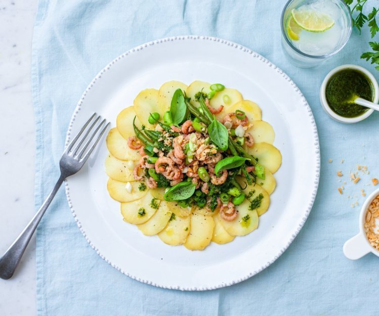 Fijn gesneden aardappel schijfjes met groene sla en verse garnalen.