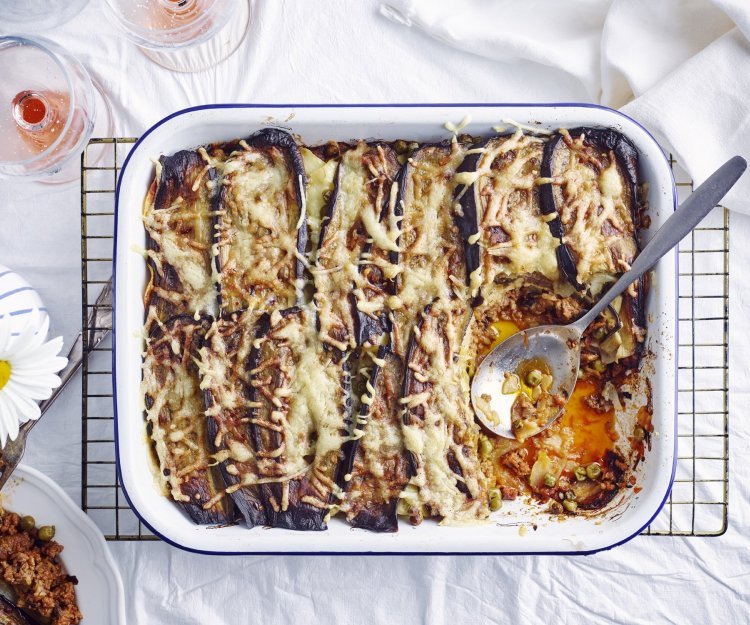 Aardappellasagne met lamsgehakt, aubergine en erwtjes Een grote ovenschotel met aardappellasagne staat op tafel. Er is al een portie uitgedeeld, maar er zijn er nog 5 te verdelen. Perfect te combineren met een glaasje rosé.