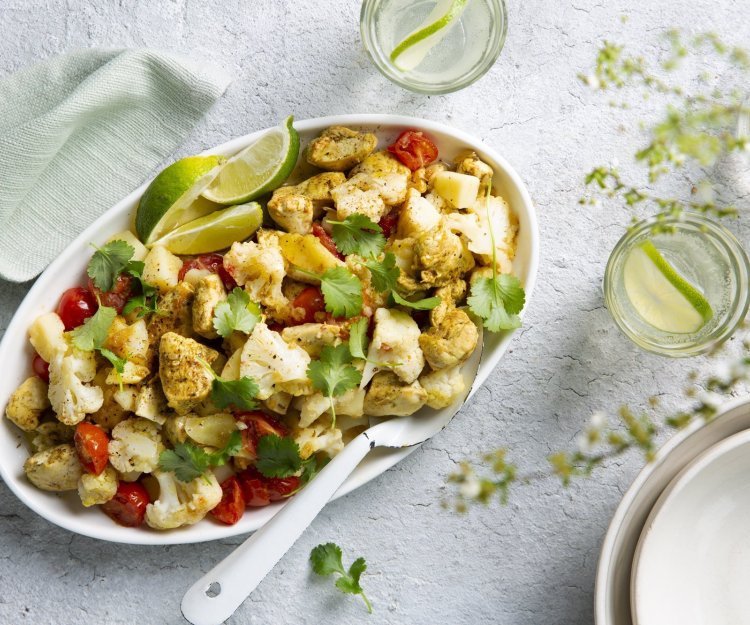 Aloo gobi met kip en aardappel Aloo gobi is een Indiase curry van aardappel en bloemkool. Wij deden er nog stukjes kip bij. Deze rijkgevulde schotel van groenten en kruiden staat op tafel met een grote witte lepel bij. Voor de afwerking werd deze schotel gepresenteerd met korianderblaadjes en limoenpartjes.