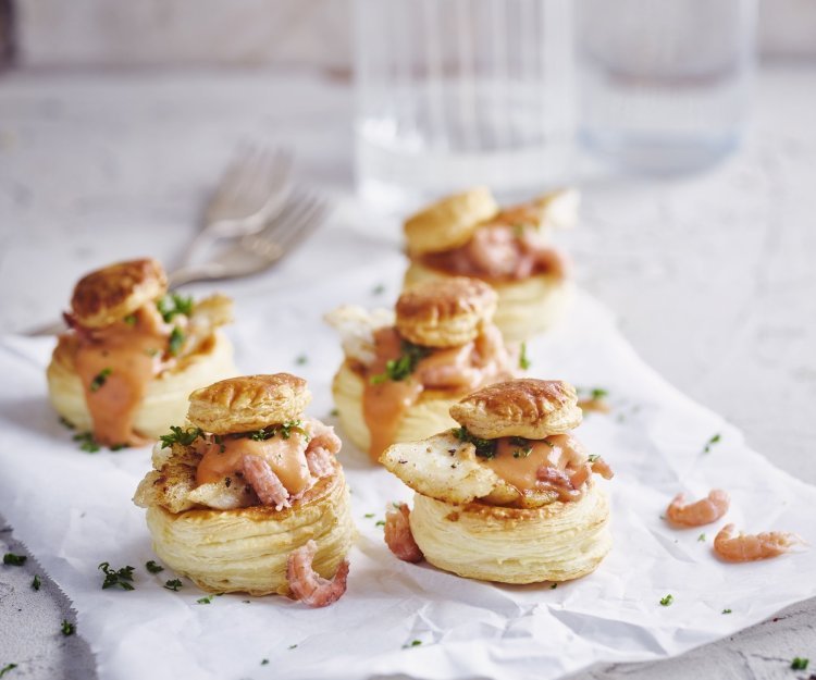 Verschillende bladerdeeghapjes staan op tafel. Ze zijn gevuld met een vol-au-vent op basis van vis, nl steenbolk. 