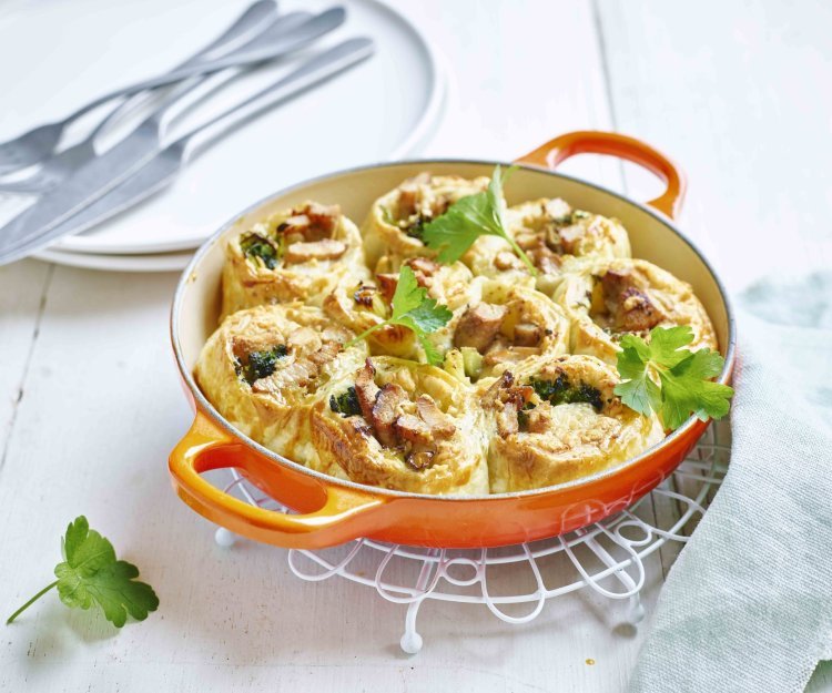Bladerdeegrolletjes met kip en broccoli Op tafel staat een gietijzeren pan, gevuld met de bladerdeegrolletjes van kip en broccoli. Fijn gerechtje om met pot op tafel te brengen.