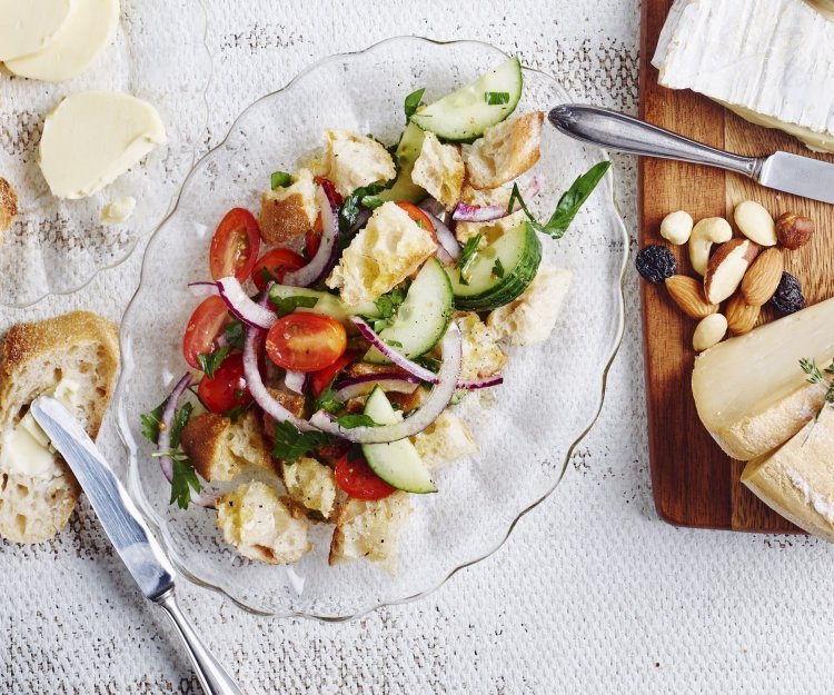 Een glazen schaaltje, ovaalvormig, gevuld met knapperige croutons, tomatenstukjes en komkommermaantjes.  