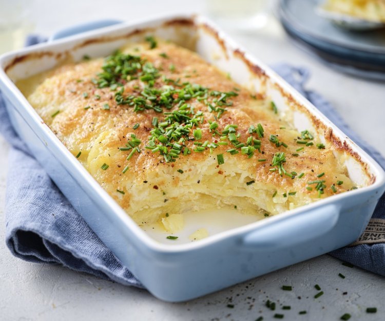 Crispy aardappelgratin De ovenschotel met gratin staat op tafel, hij heeft een lichtblauwe kleur. De aardappelschijfjes zijn lekker crispy gebakken, doordat we ze in de oven klaarmaken met minder room. De ovenschotel is afgewerkt met verse fijngehakte bieslook.