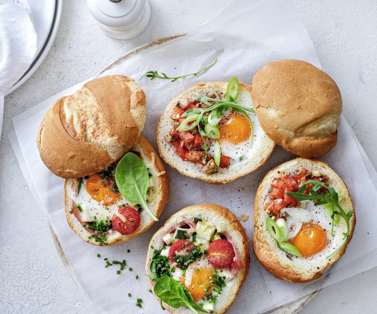Eieren uit de oven met ham of tomatensalsa Gevulde broodjes met een eitje erin, staan op tafel te blinken! We maakte een versie met gekookte ham, courgette en tomaatjes. En onze tweede is er eentje met pittige tomatensalsa en rucola, heerlijk!