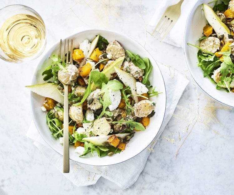 Feestelijke aardappelsalade met pompoen, peer en geitenkaas Een heerlijke aardappelsalade geserveerd in een diep wit bord. De kleuren zijn heerlijk fris en zonnig om je feestmenu te laten stralen. Groen, oranje en wit zijn hier de kleurtoppers.