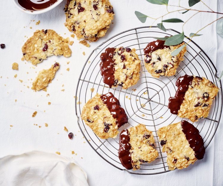 Florentine koekjes met kersen, chili, gember en chocolade Krokante amandelkoekjes liggen af te koelen op een taartrooster. Ze zijn mooi goudgeel gebakken en zijn 1/4 gedipt in gesmolten chocolade.