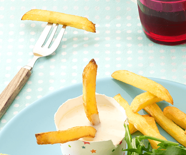 Zelfgemaakte mayonaise op een blauw bord staat een potje gevuld met mayonaise om je frietjes in te dippen.