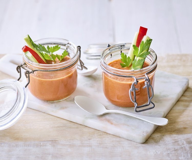 Gazpacho Twee bokaaltjes met gazpacho staan op een marmer plankje, een ideaal alternatief voor te weinig glazen. We gaven de gazpacho een feestlook met staafjes komkommer en paparika in het bokaaltje te laten op springen.