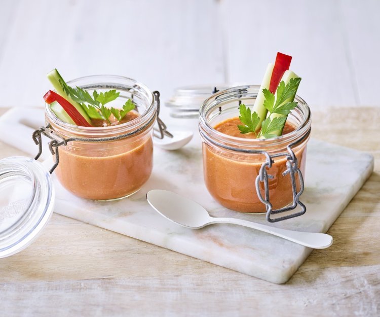 Twee bokaaltjes met gazpacho staan op een marmer plankje, een ideaal alternatief voor te weinig glazen. We gaven de gazpacho een feestlook met staafjes komkommer en paparika in het bokaaltje te laten op springen.  