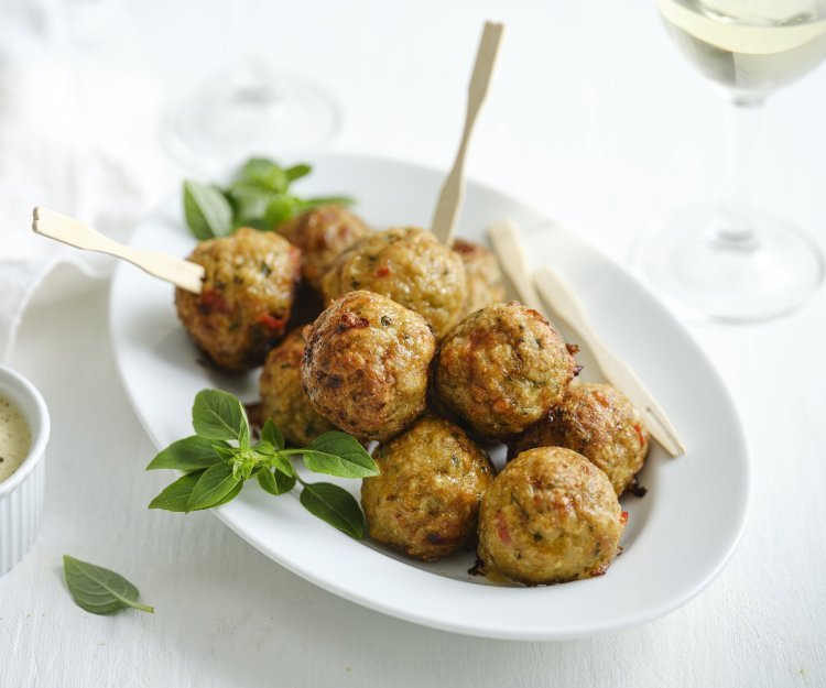 Gehaktballetjes van kip met kaas uit de airfryer Op een wit bordje liggen meerdere gehaktballetjes, sommigen met een prikkertje zodat je meteen van deze knapperds kunt proeven.