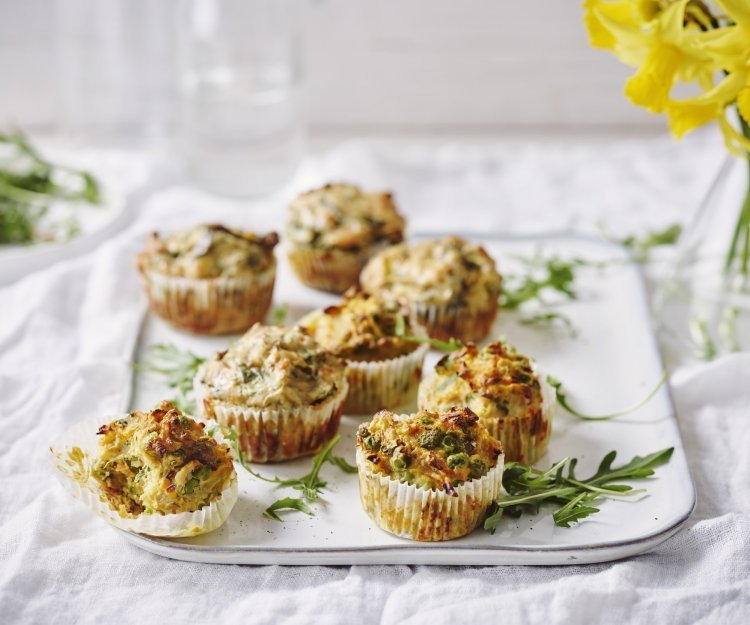 Hartige cupcakes op een dienplateau gepresenteerd. Achteraan staat een vaasje met Narcissen te schitteren.