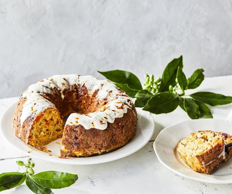 Een tulband cake met groenten als bijgerecht bij je middagmaal, dat is pas een feestmaaltijd! Wij maakten eentje met pompoen, rode biet, Belgische kaas en kastanjes. Hij staat op een witte houten tafel op een wit groot bord, de cake is afgewerkt met een garnering van zure room.