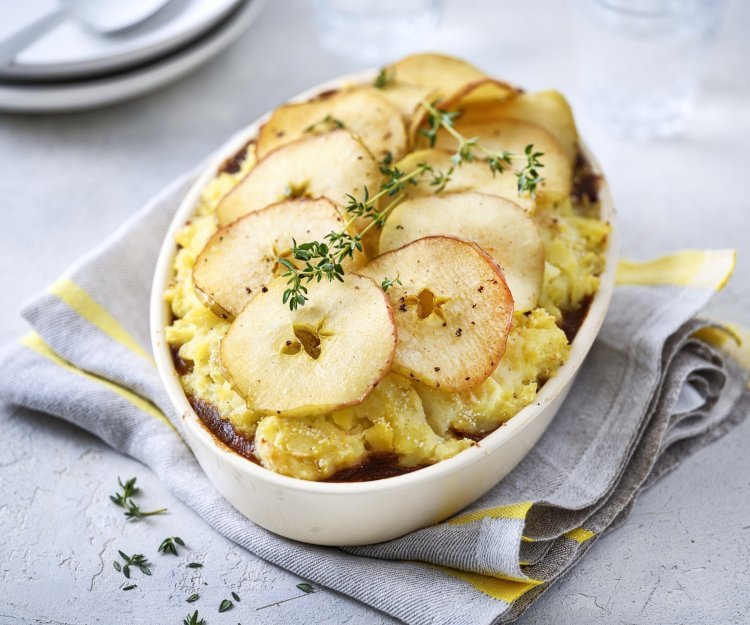 Jachtschotel met schijfjes appel Op tafel staat een ovale witte ovenschotel gevuld met onderaan het stoofpotje, hierop de aardappelpuree en tenslotte de appelschijfjes. Dit geeft een mooi beeld, niet alleen om naar te kijken ook om meteen te beginnen eten. Het gerechtje werd afgewerkt met verse takjes tijm.