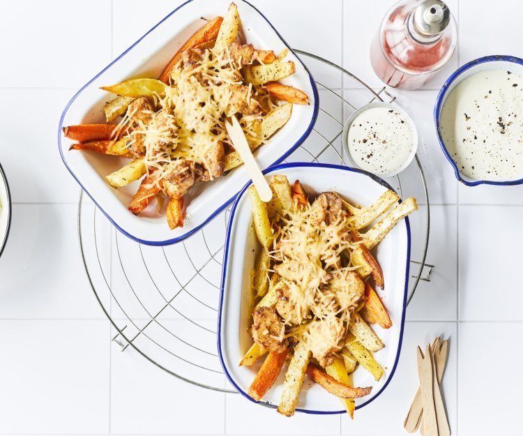 Kapsalon met konijn en groentefrietjes Twee pitaschotels staan op het aanrecht met de ijsbergsla, het yoghurtsausje en de chilisaus langs. Er liggen houten vorkjes langs om meteen van start te gaan aan dit gezond kapsalon.