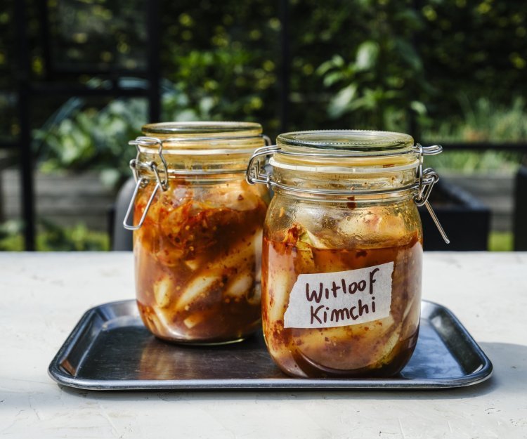 Er staan twee weckpotten op een inoxe plateau gevuld met kimchi. Hij is roodkleurig door de toevoeging van chilisaus. 