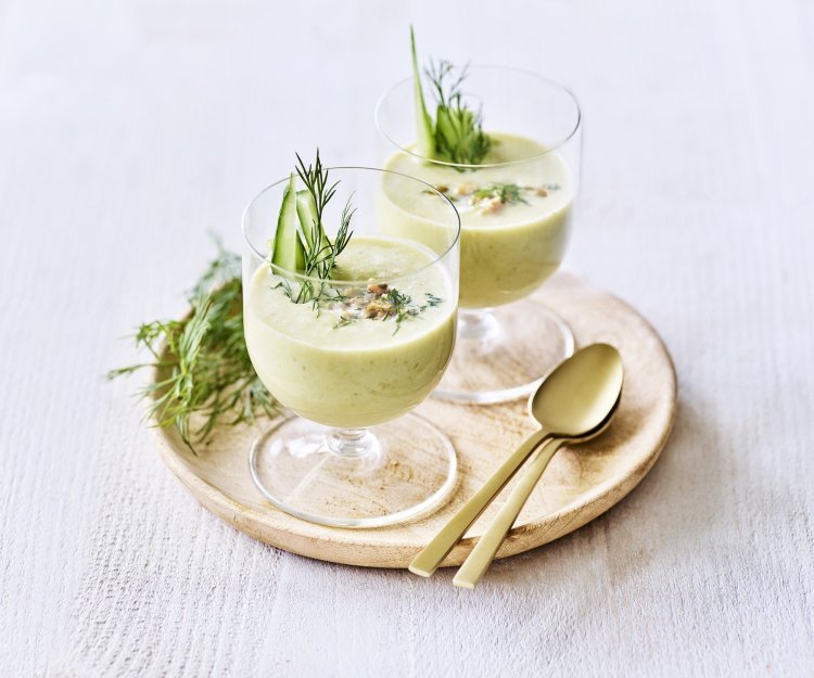 Koude komkommersoep met yoghurt Twee glaasjes gevuld met een koud soepje ogen niet alleen prachtig, ze smaken ook heerlijk fris! Ze heeft een lichtgroene kleur door de komkommer, prei en yoghurt. Het soepje is afgewerkt met walnoten, dille en staafjes komkommer.