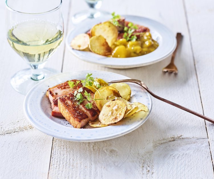 Krokant buikspek met homemade chips en Belgische pickles Er staan twee bordjes op tafel gevuld met krokant buikspek, krokante aardappelchips en een schep Belgische pickles. Een voorgerechtje boordevol Belgische topproducten!