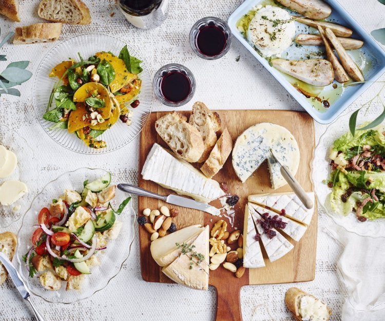 Originele kaasschotel met warm geitenkaasje en partjes peer De tafel staat klaar om aan te vallen. Er staat een kaasplank op met Belgische kazen en verschillende bijgerechten met fruit en groenten. Wijn en brood mogen natuurlijk niet ontbreken bij deze pittige kazen.