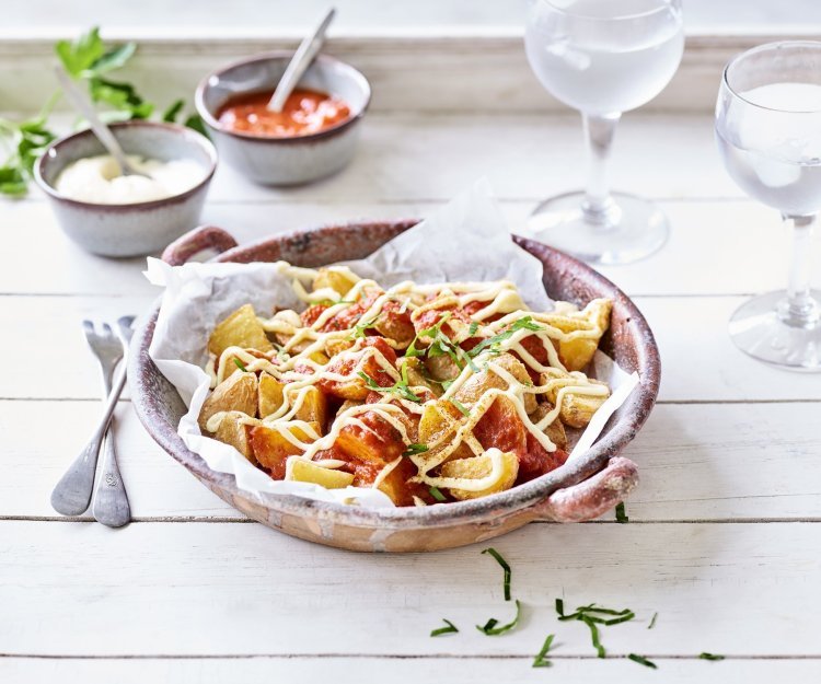 Patatas bravas Heerlijke patatas bravas geserveerd in een groot diep bord, afgewerkt met een pittige tomatendip en aïoli. Twee gekoelde watertjes staan rechts van het bord. Klaar om de tapas tafel aan te vallen.