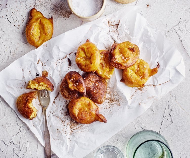 Op het aanrecht liggen enkele pompoenbeignets op een wit boterpapiertje. Ze hebben een mooie oranje gloed, net gouden beignets. Er ligt een vorkje langs meteen te prikken en te eten. 