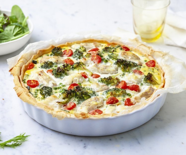 Het lijkt alsof de quiche net uit de oven komt. Ze staat nog ongesneden op het aanrecht klaar om aan te snijden en te smullen van deze hartige taart met broccoli, tomaatjes en schelvis.